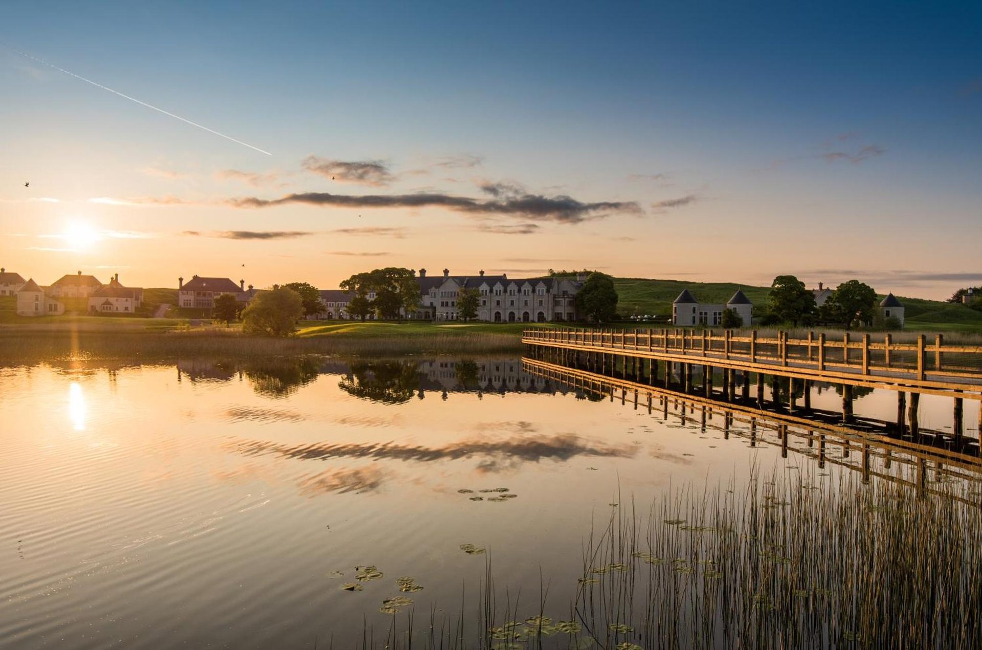 Low sun over Lough Erne at first light, the resort on the far shore mirrored in still water.